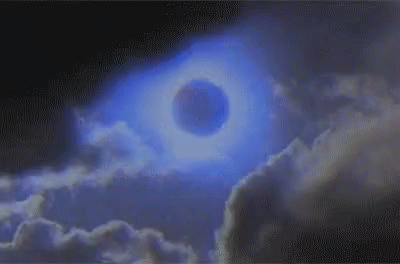 A gif of dark clouds folding in on a purplish-blue moon against a purpleish-blue sky.